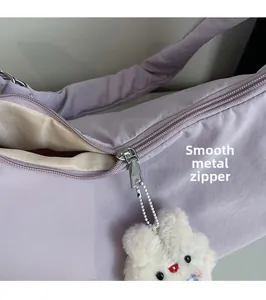 Detail of smooth metal zipper and white plush bunny charm on soft purple crossbody bag