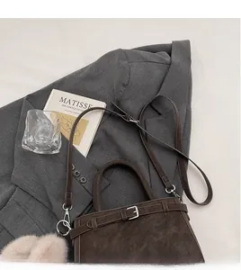 Détail du sac à main en daim marron foncé avec bandoulière réglable et boucle en métal