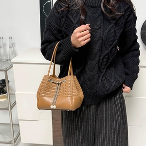 Vue détaillée d'un sac seau marron avec texture tissée, base en cuir et perle décorative