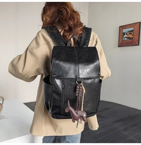 Detail of black faux leather backpack with animal charm and vertical zip pocket