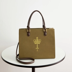 Close-up of olive green tote bag with luxury crown logo and dark brown leather handles