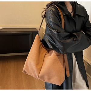 Detail of tan suede tote bag featuring side pockets and high-capacity minimalist design
