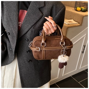 Detail of vintage brown suede bowling bag featuring silver hardware and a fluffy pom charm