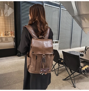 Detail of dark brown leather backpack with retro charm and cute dachshund dog charm