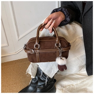 Detail of vintage brown suede bowling bag featuring silver buckles and a heart charm