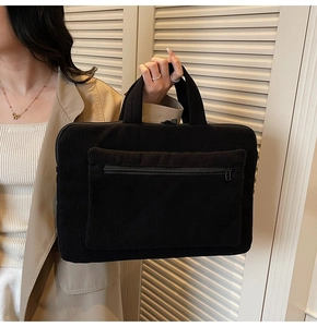Close-up of black corduroy laptop bag featuring a horizontal front zipper pocket and handle