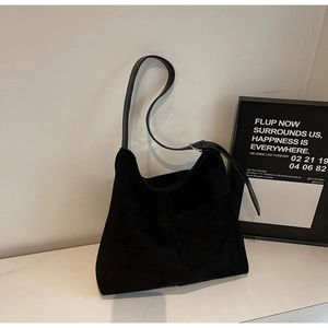 Detailed view of black suede hobo bag with leather strap and minimalist front pocket design