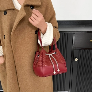 Détail du sac seau rouge tressé avec chaîne argentée et accents de perles