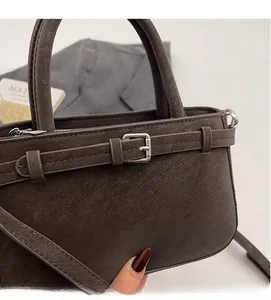 Gros plan du sac à main marron foncé mat montrant sa texture souple et sa boucle décorative