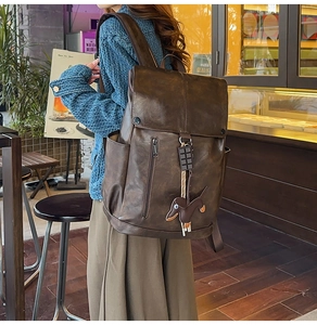 Detail of a vintage dark brown backpack with creative charms in a cafe setting