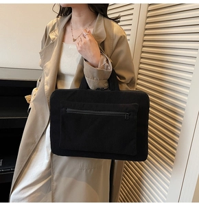 Detail of black corduroy laptop tote bag with reinforced handles and front zipper pocket