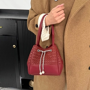 Détail du sac seau rouge tissé avec chaîne argentée et cordons ornés de perles