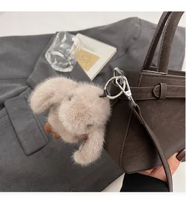 Gros plan d'un charm lapin en peluche sur un sac à main en cuir marron élégant
