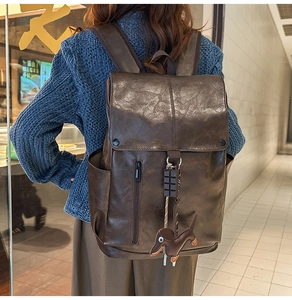 Detail of a brown leather backpack with vertical zipper and cute dachshund dog charm