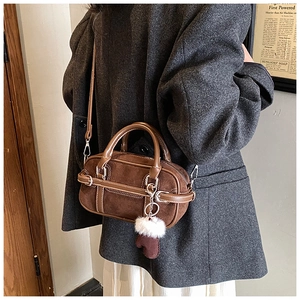 Brown suede bowling bag with vintage leather handles and plush charm detail on strap
