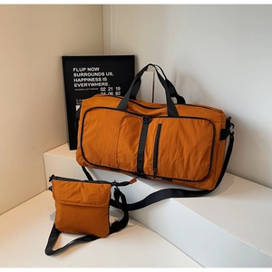 Macro detail of a large orange duffel bag and crossbody set on minimalist white steps