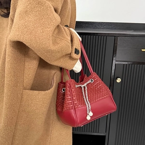 Détail du sac seau rouge avec texture en cuir tressé et cordon chaîne à perles