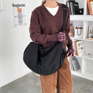 Detail of black nylon dumpling bag with adjustable strap in casual lifestyle scene