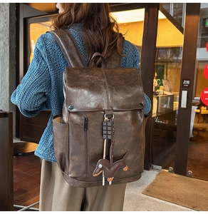 Detail of vintage brown leather backpack with a dog charm and side pocket texture