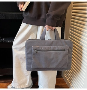 Détail du sac à main gris en velours côtelé pour ordinateur portable porté par un mannequin
