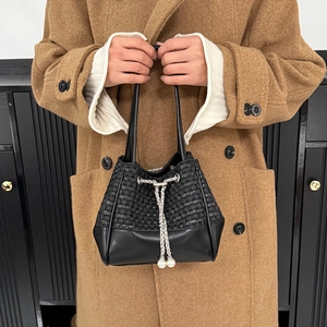Détail d'un sac seau en cuir tressé avec cordon de serrage argenté et perles