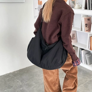 Close-up of a black nylon oversized crossbody dumpling bag on a person for daily use