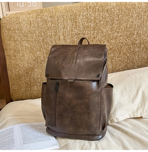 Close-up of deep brown vintage leather backpack with front zipper and buckle flap