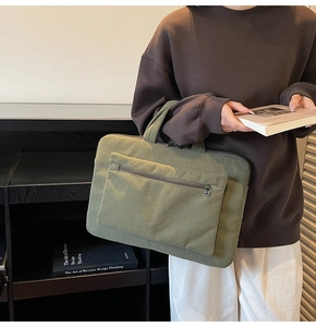 Detail view of grass green corduroy laptop bag with reinforced handles and front pocket