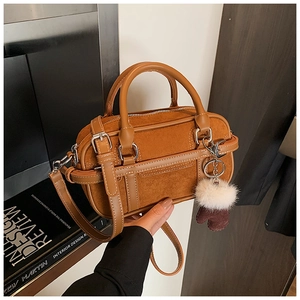Detail of vintage brown bowling bag with suede stitching and plush ball charm accessory