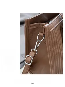 Detailed macro view of the brown leather texture and silver metallic buckle on tote bag