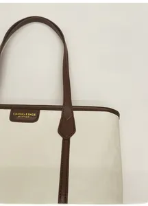 Détail du sac cabas en cuir crème avec anses marron et lettrage doré élégant