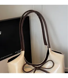 Détail du sac cabas en PU crème avec bandoulières marron foncé et nœud en cuir