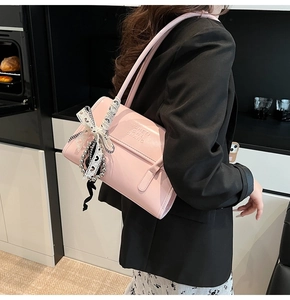 Detailed view of pink leather shoulder bag with checkered bow and silver bead charm accessories