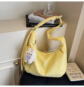 Detail of yellow nylon dumpling bag with adjustable strap and white rabbit charm decoration