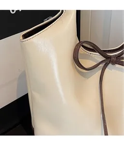 Détail d'un sac cabas en cuir blanc cassé avec nœud marron et logo GONG en relief