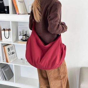 Close-up of a large red nylon dumpling bag worn as a casual crossbody commute bag