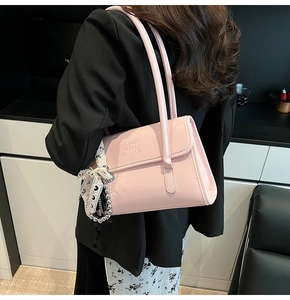 Detail of light pink shoulder bag with a polka dot scarf tied on the strap