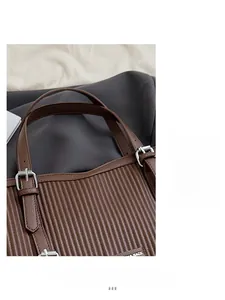 Detail of dark brown pleated tote bag featuring adjustable strap and silver metal hardware