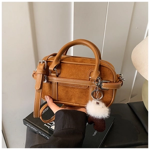 Detailed side view of vintage brown bowling bag with plush pom-pom and heart charm