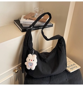 Detail of black nylon dumpling bag featuring a soft padded texture and cute rabbit charm