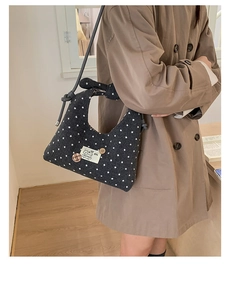 Detail van een zwarte hobo-tas met stippen, stoffen patch en slanke schouderriem