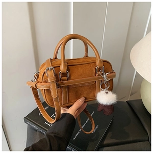 Detailed macro view of the brown suede bowling bag with a white fluffy keychain accessory