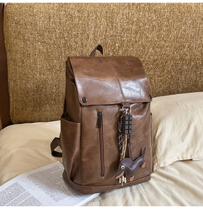 Detail view of retro brown leather backpack with textured finish and cute dog pendant