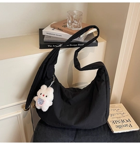 Detail shot of black crescent moon bag with zipper and cute white bunny plush pendant