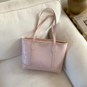 Gros plan d'un sac cabas en cuir PU rose clair avec étiquette sur un canapé