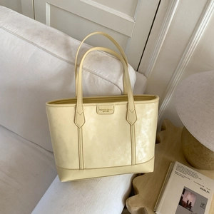 Détail d'un cabas minimaliste jaune clair avec étiquette logo sur un canapé blanc