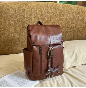 Detailed view of brown leather backpack with front zipper pocket and dog pendant