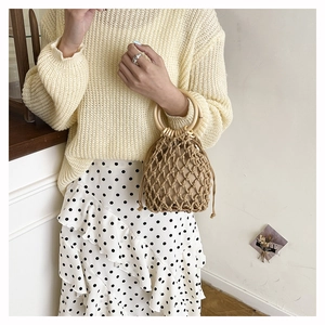 Detail of woven straw bucket bag with wooden handle and drawstring liner for summer