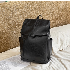 Detail shot of the black leather texture and front zipper pocket on a casual backpack