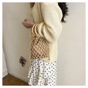 Vue latérale d'un sac seau tissé à la main avec poignées en bois et pochette beige